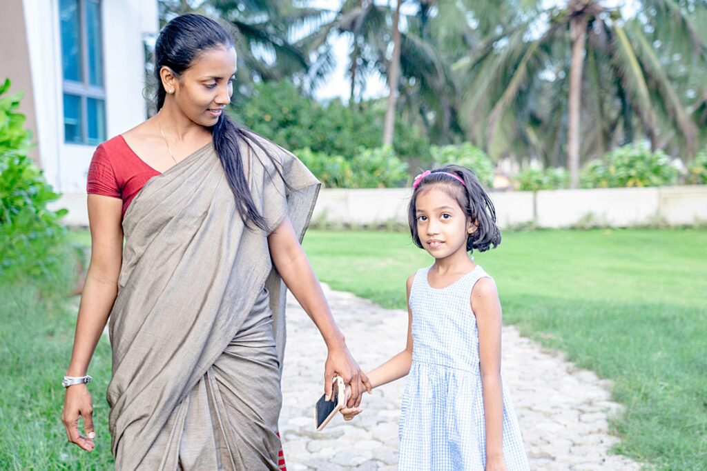 Photo of a Woman Wearing a Traditional Indian Outfit and Holding a Hand of a Little Girl